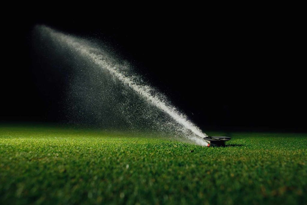 automatic sprinkler watering a lawn at night